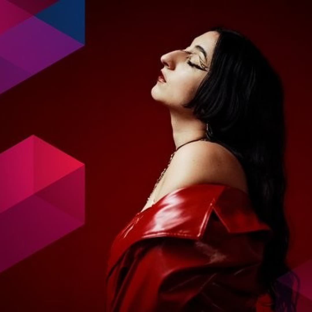 Person with long black hair and closed eyes, wearing an off-shoulder red jacket, set against a dark red background with pink geometric shapes.